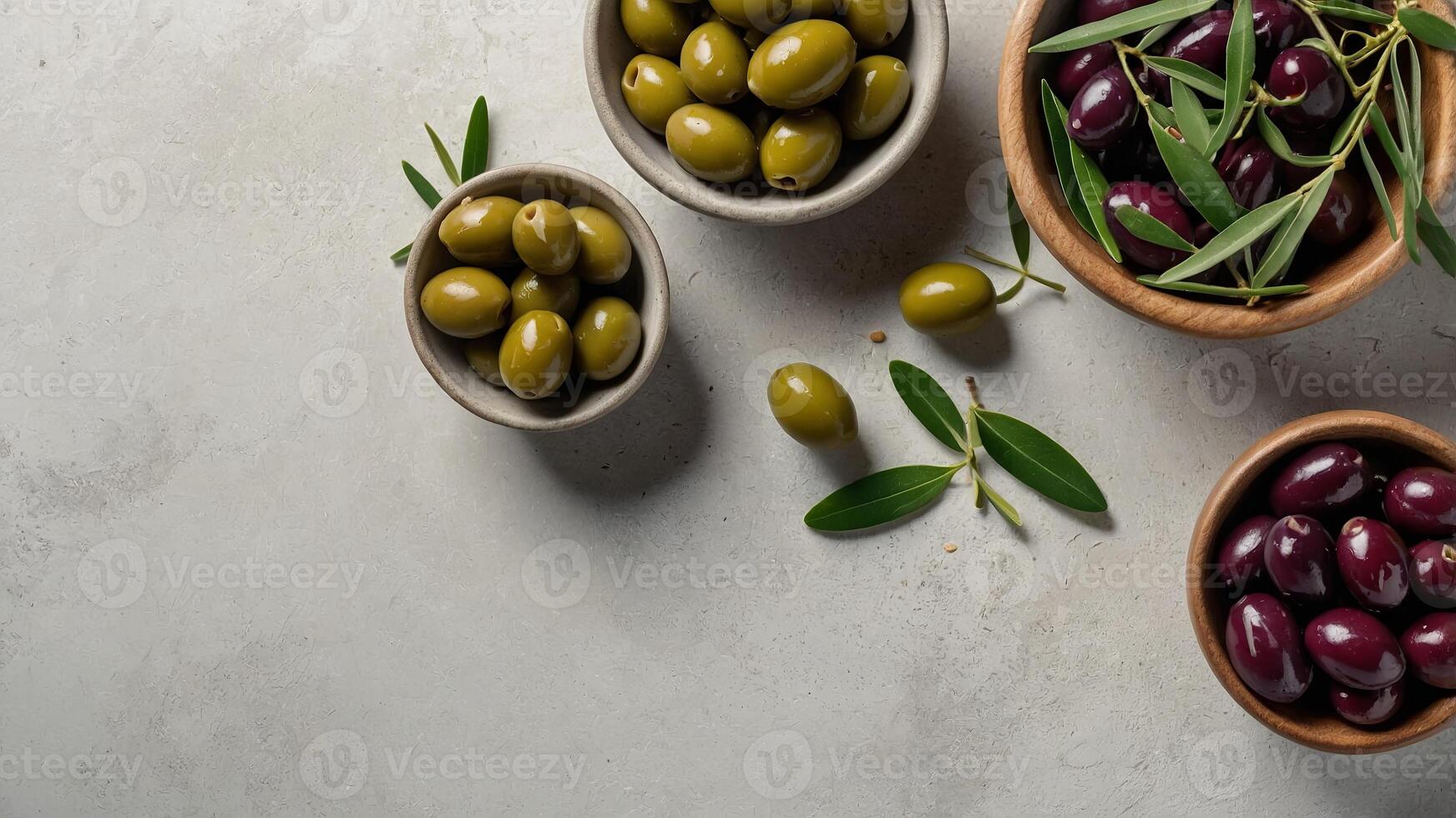 Different olives in bowls on white concrete background Top view of olives, olive leaves Diet food concept Banner. photo