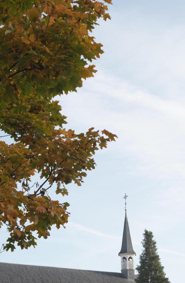 Hasselt, Limburg-Belgium. 20-10-2021. a small church building in the city center. Fragment of the roof on an autumn background sky photo
