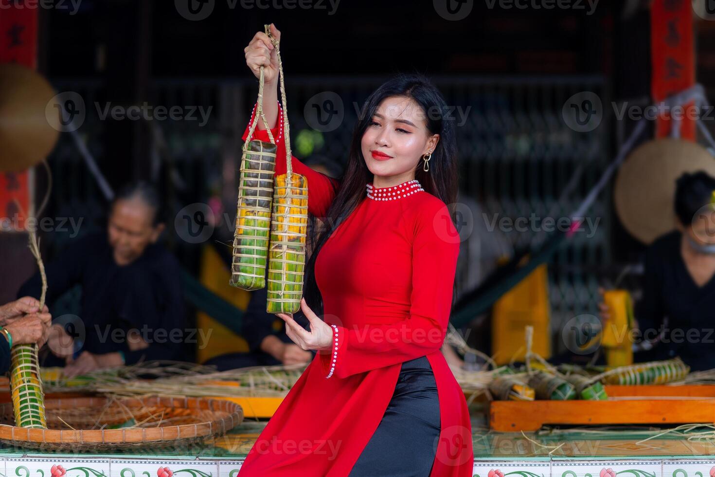 Vietnamese girl with Ao Dai dress sitting in traditional house of Vietnam and making Tet Cake, Tet food outdoor with old woman. Traditional Vietnamese New Year Tet food. photo