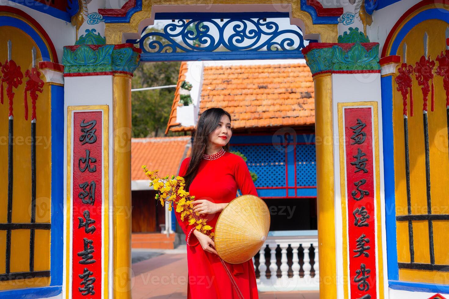 Vietnamese girl with Ao Dai dress standing in traditional house of Vietnam. Text in photo mean best wishes to family, happiness, prosperity, health. Tet holiday and New Year.