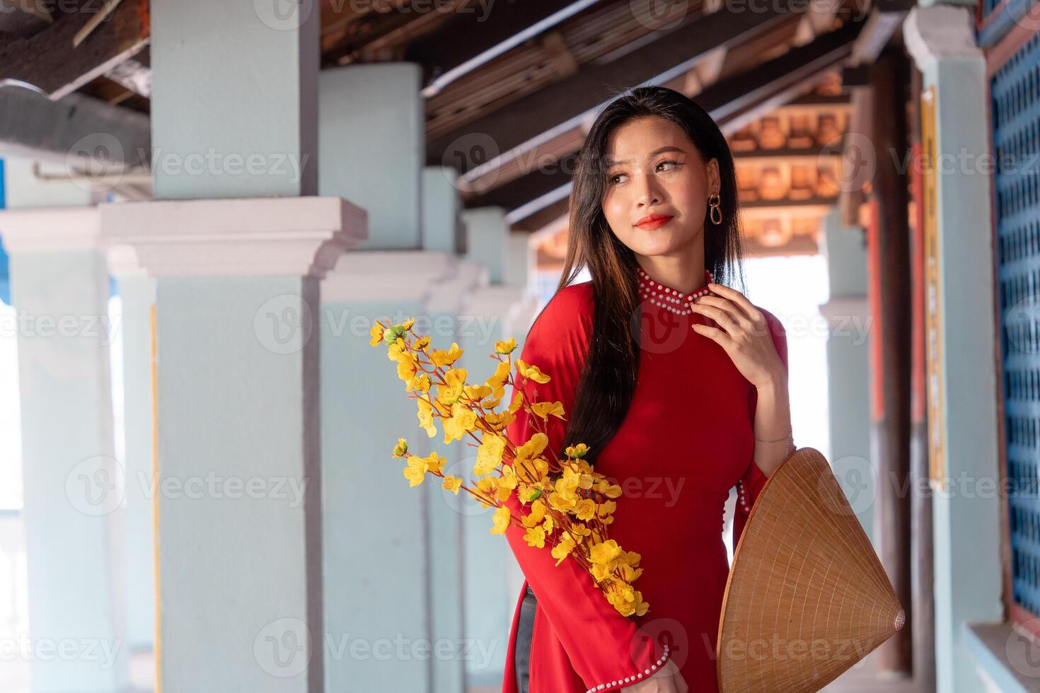 Vietnamese girl with Ao Dai dress standing in traditional house of Vietnam. Text in photo mean best wishes to family, happiness, prosperity, health. Tet holiday and New Year.