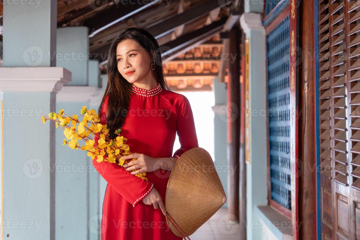 Vietnamese girl with Ao Dai dress standing in traditional house of Vietnam. Text in photo mean best wishes to family, happiness, prosperity, health. Tet holiday and New Year.