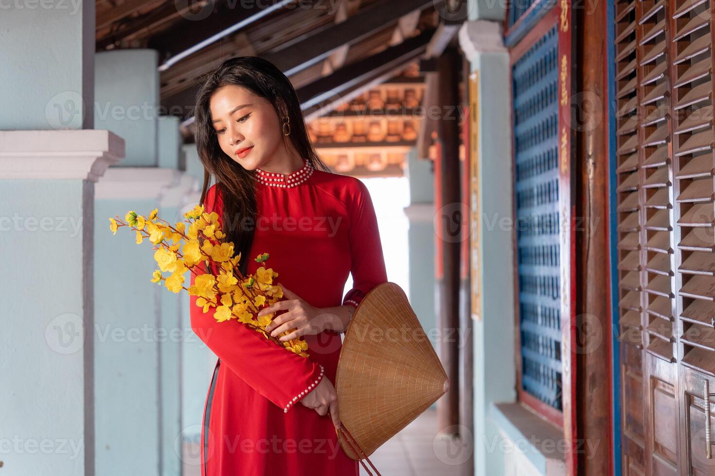 Vietnamese girl with Ao Dai dress standing in traditional house of Vietnam. Text in photo mean best wishes to family, happiness, prosperity, health. Tet holiday and New Year.