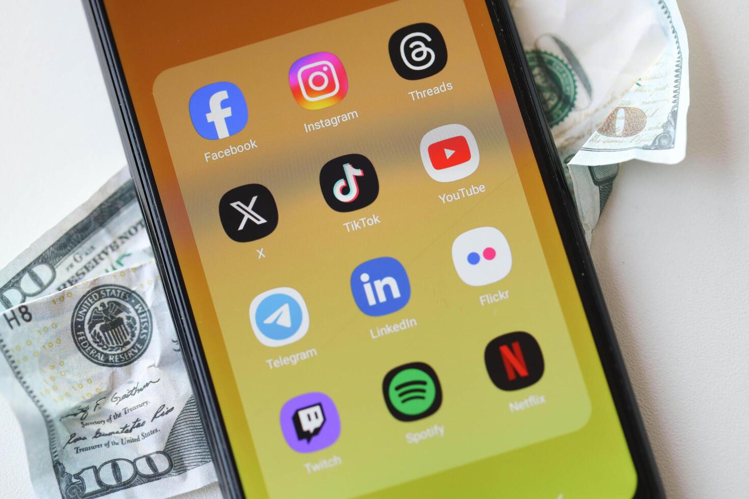 KYIV, UKRAINE - FEBRUARY 28, 2024 Social Media on smartphone display and crumpled dollar bill photo