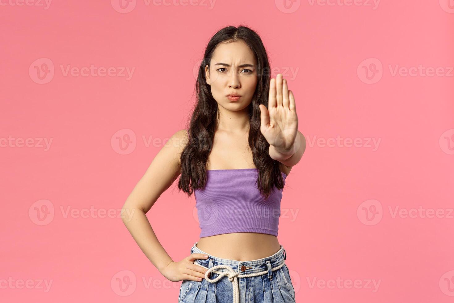 Stop right there. Serious-looking stylish young modern girl telling to quit it, raise hand in prohibition, give warning, disagree with person bad behaviour, frowning want to prevent something photo