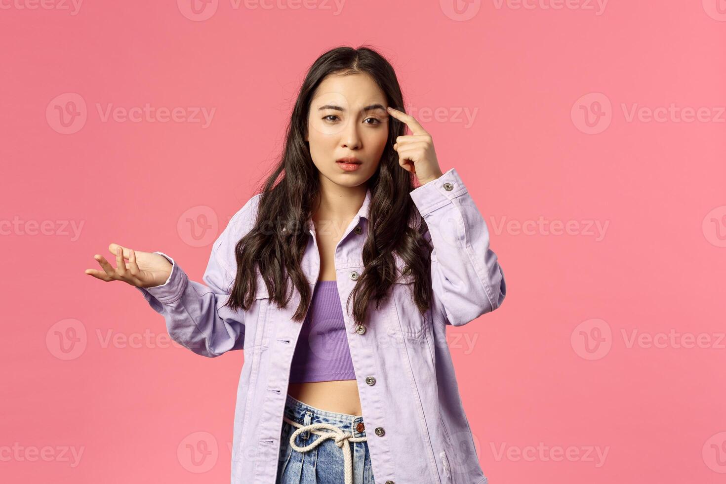 Are you dumb. Displeased annoyed young stylish girl scolding someone for making stupid mistake, not thinking before action, shrug with dismay, tap temple bothered with crazy person thoughts photo