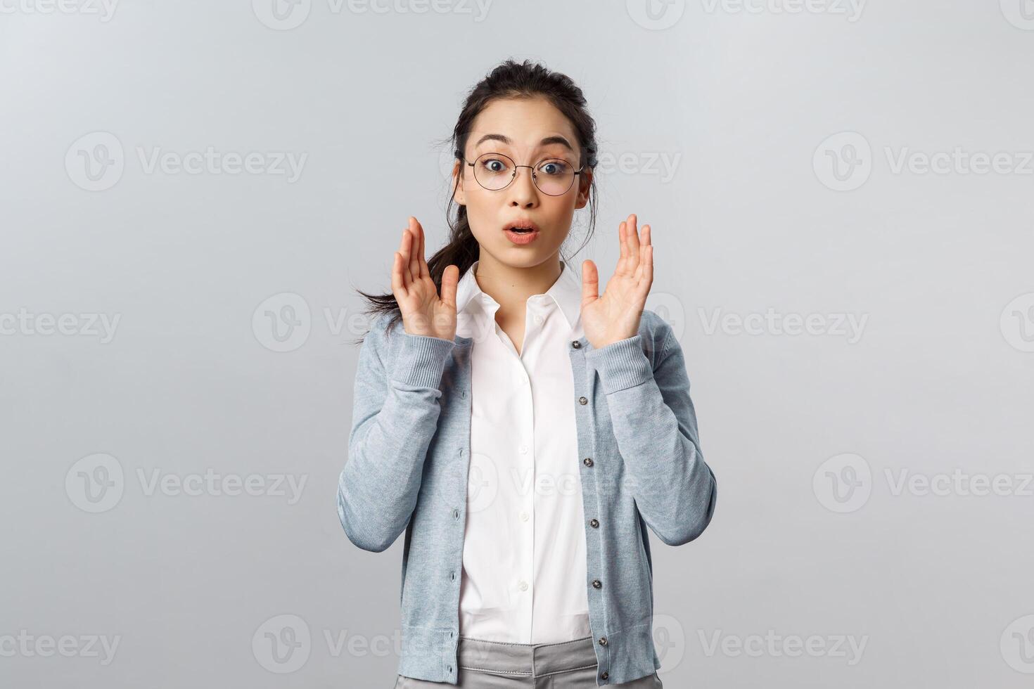 Surprised and amazed asian pretty woman put-on glasses and finally can see clear, raise eyebrows in wonder, gesturing hands and open mouth fascinated, picking eyebwear at optician store photo