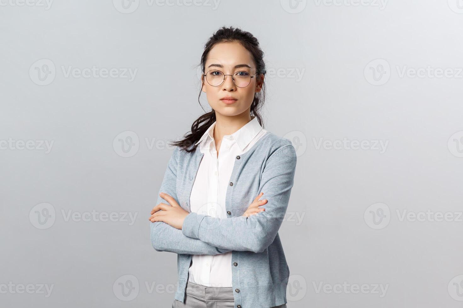 Serious-looking determined attractive asian woman, tutor or teacher starting online lesson with class standing self-assured with normal focused expression, cross arms on chest photo