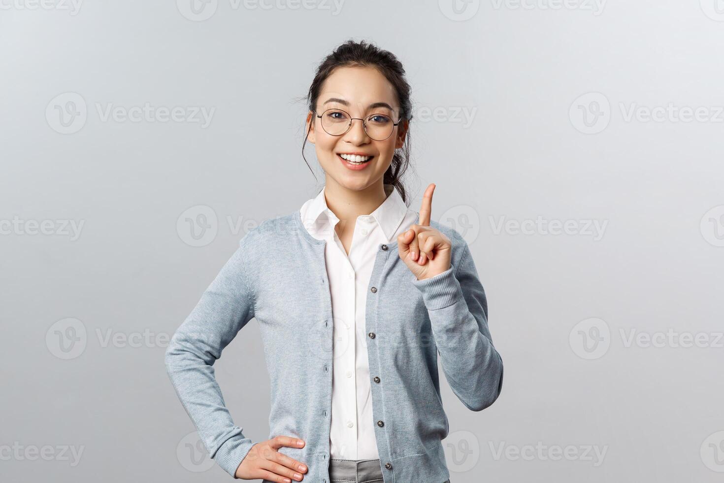 Education, studying and online classes concept. Rule number one. Cheerful pretty asian girl explaining exercise to class, raising index finger, pointing up, add a suggestion or making point, smile photo