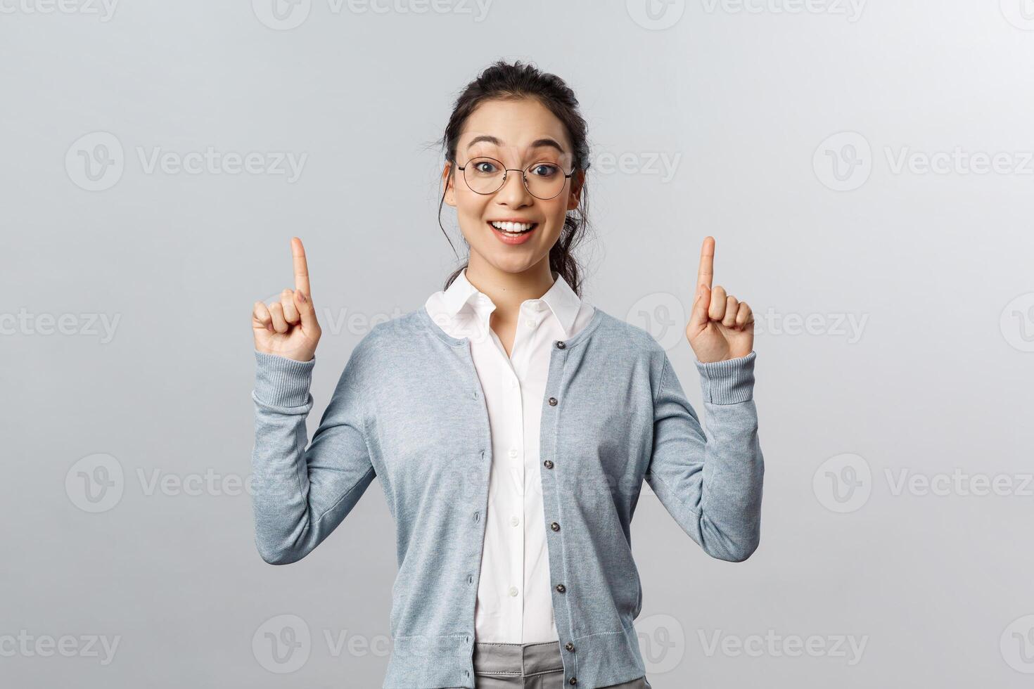 Excited, surprised asian woman talking about brand new product in store, raise eyebrows up wondered, smiling amused pointing fingers up, recommend product, advice check-up and click link photo