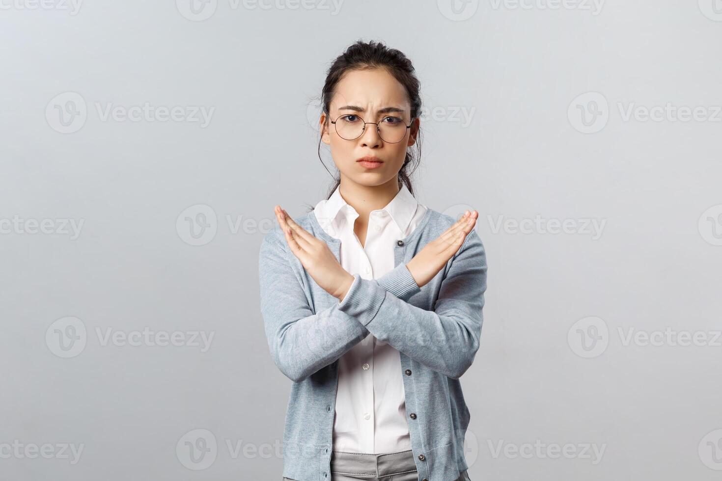 We must end it. Serious-looking determined young confident asian woman, making cross stop sign and looking concerned camera, prohibit something, disagree, trying restrict from going outside photo