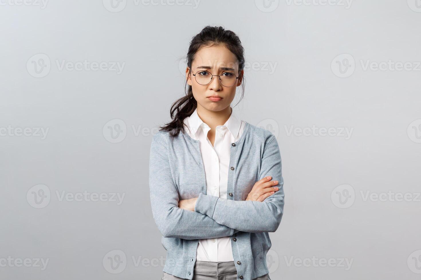 Portrait of offended insecure and timid cute asian girl complaining on cruel customer being rude to her, cross hands over chest defensive and upset, frowning gloomy, feel upset grey background photo
