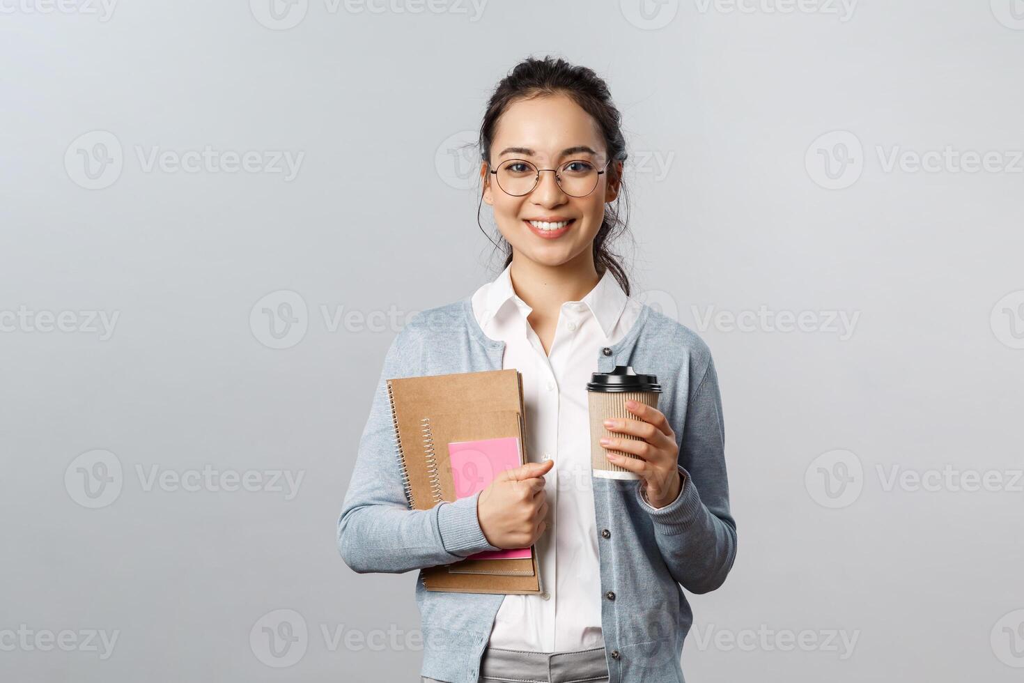 Education, teachers, university and schools concept. Attractive young smiling woman working, teaching students with online app, carry books and notebooks, drinking coffee on her way to class photo