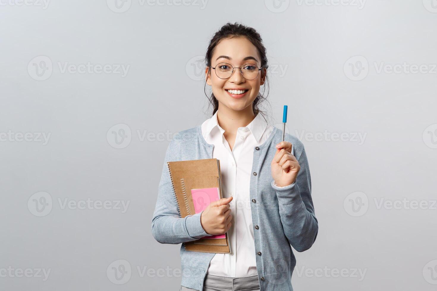 Education, teachers, university and schools concept. Cute nerdy asian girl adding point, have solution to equation, raising pen to say her thought smiling, carry books and notebooks studying photo