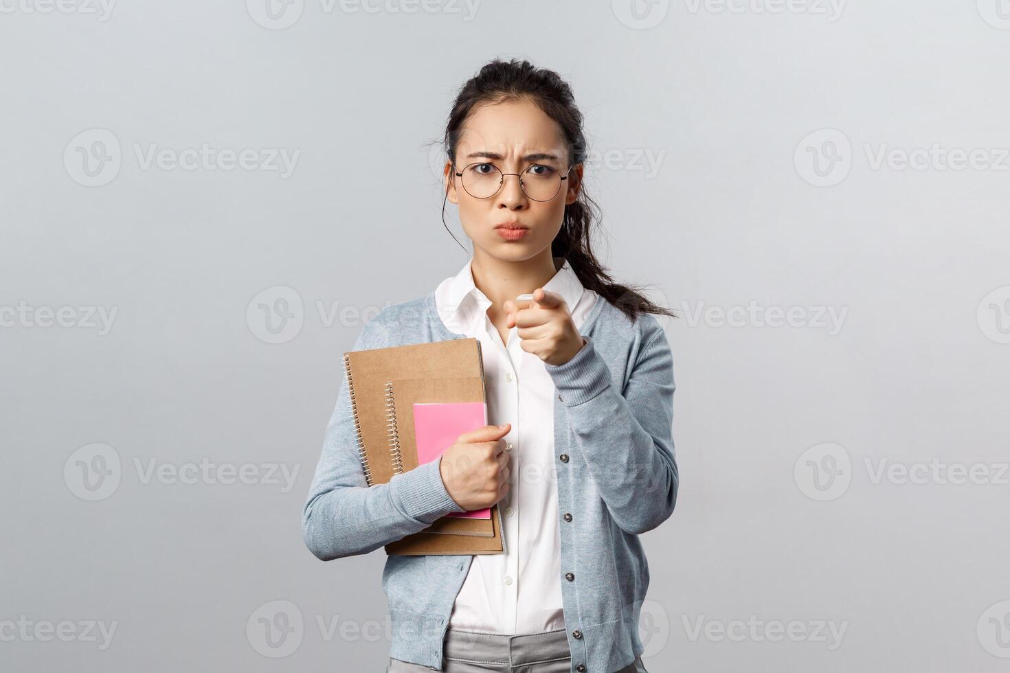 Education, teachers, university and schools concept. Portrait of angry displeased young female tutor scolding student bad behavrious, blame someone point fingers, frowning displesed, carry notebooks photo