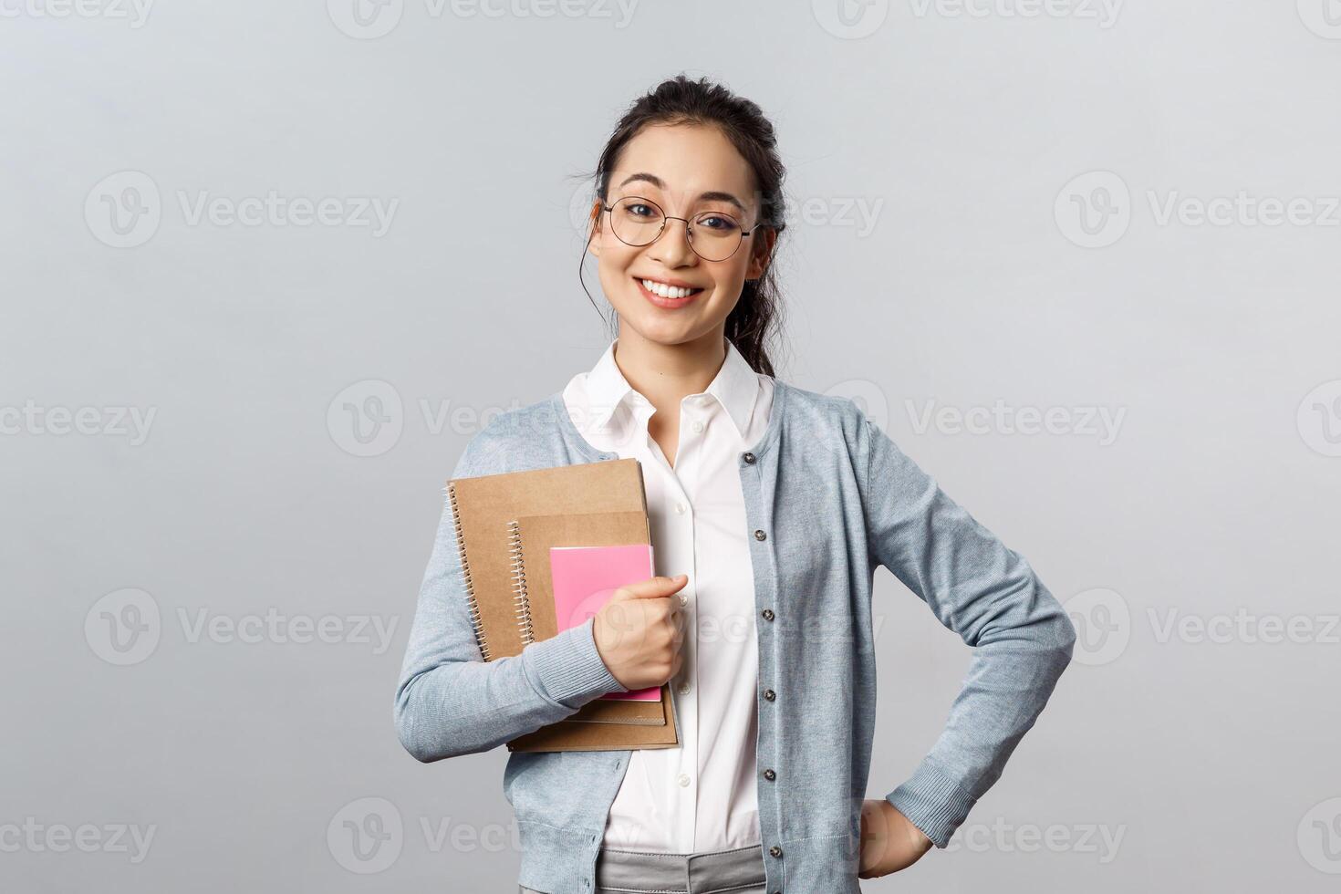 Education, teachers, university and schools concept. Upbeat happy female tutor likes teaching students, standing enthusiastic with prepared study material, hold notebooks smile broadly photo