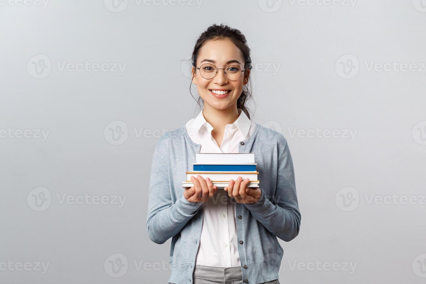 Education, teachers, university and schools concept. Smart and enthusiastic asian female student studying for exams, carry piles of books to prepare homework for classes, smiling happy photo
