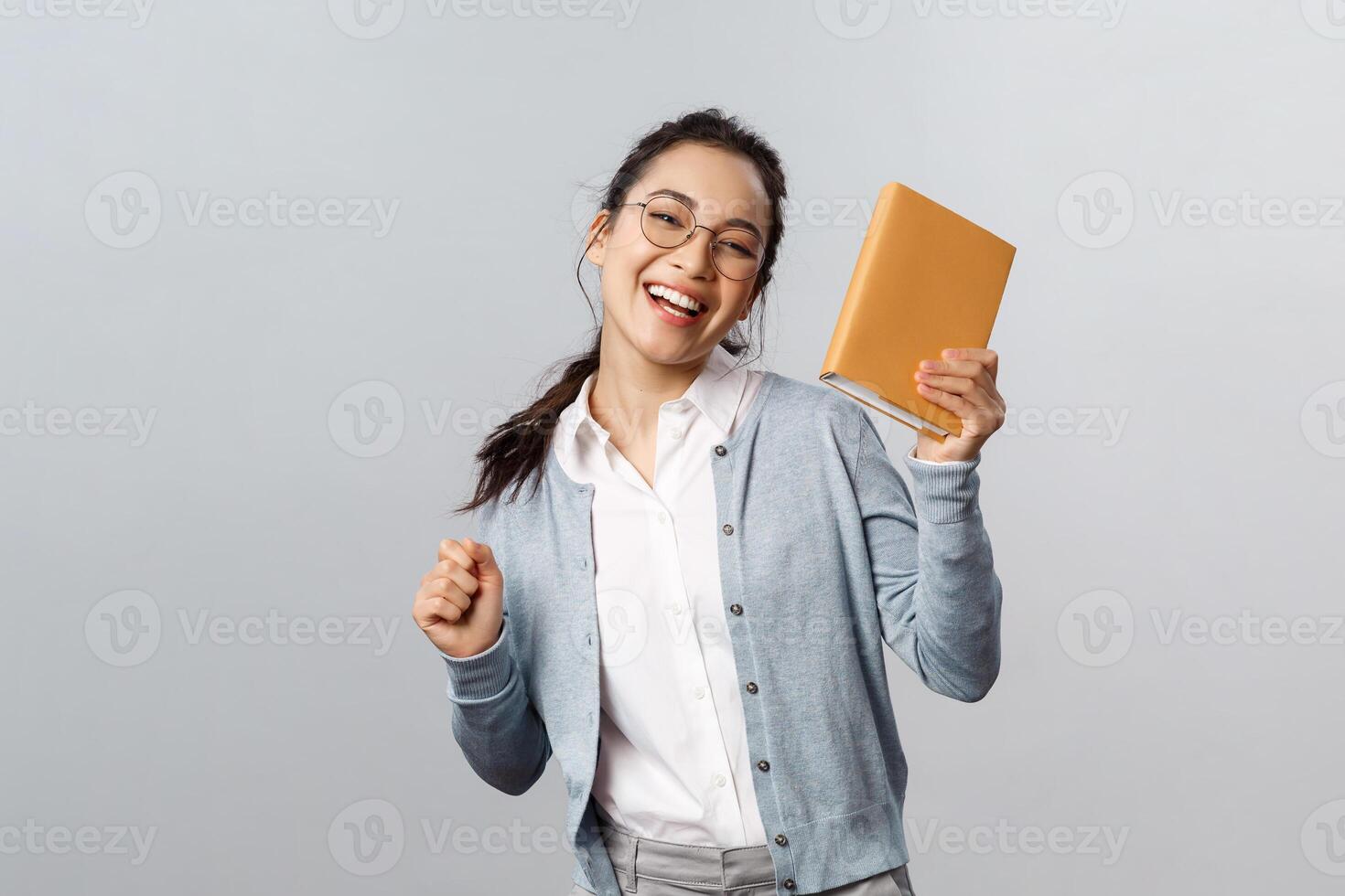 Education, teachers, university and schools concept. Cheerful carefree, smiling asian female student celebrating end of semester, dancing with planner or notebook, smiling rejoicing photo