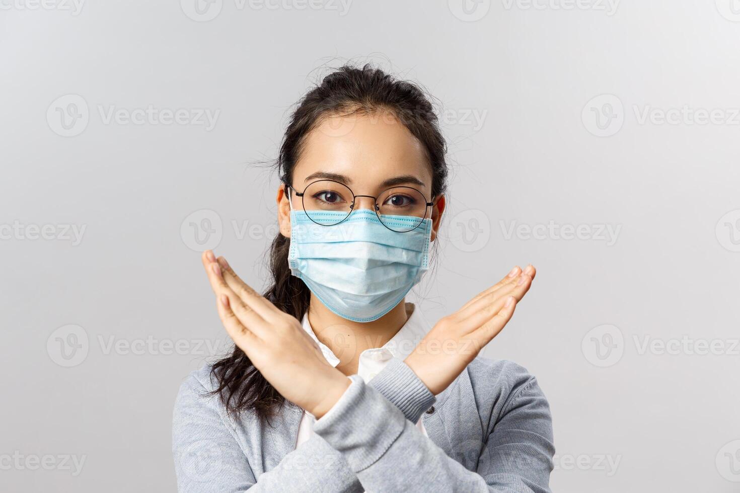 Covid19, virus, health and medicine concept. Stop going outside, social distancing and quarantine is important, girl in medical mask asking people to stay home, cross hand in enough, prohibition photo