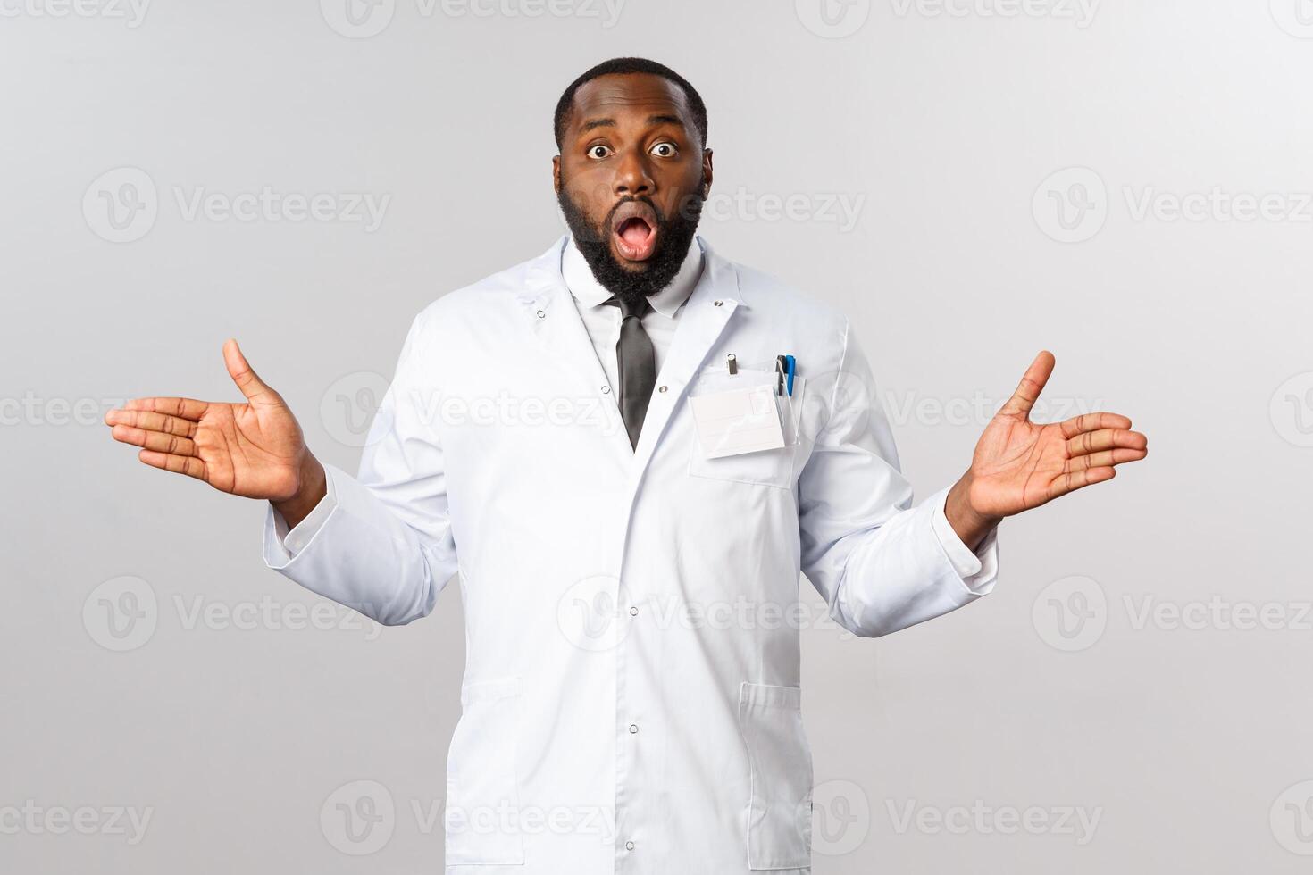 Covid19, healthcare and clinic concept. Portrait of surprised african-american doctor, spread hands sideways puzzled, gasping and staring startled camera, cant understand how it happened photo