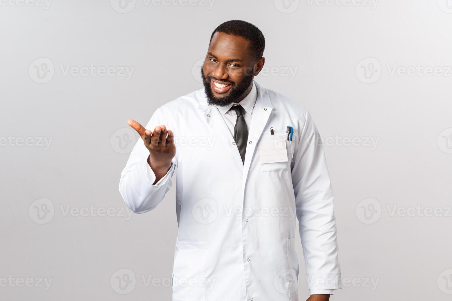 Pleased to meet you, tell me your problem. Portrait of polite and friendly, charismatic african-american doctor inviting patient to sit and explain what bothered them, working in hospital or clinic photo