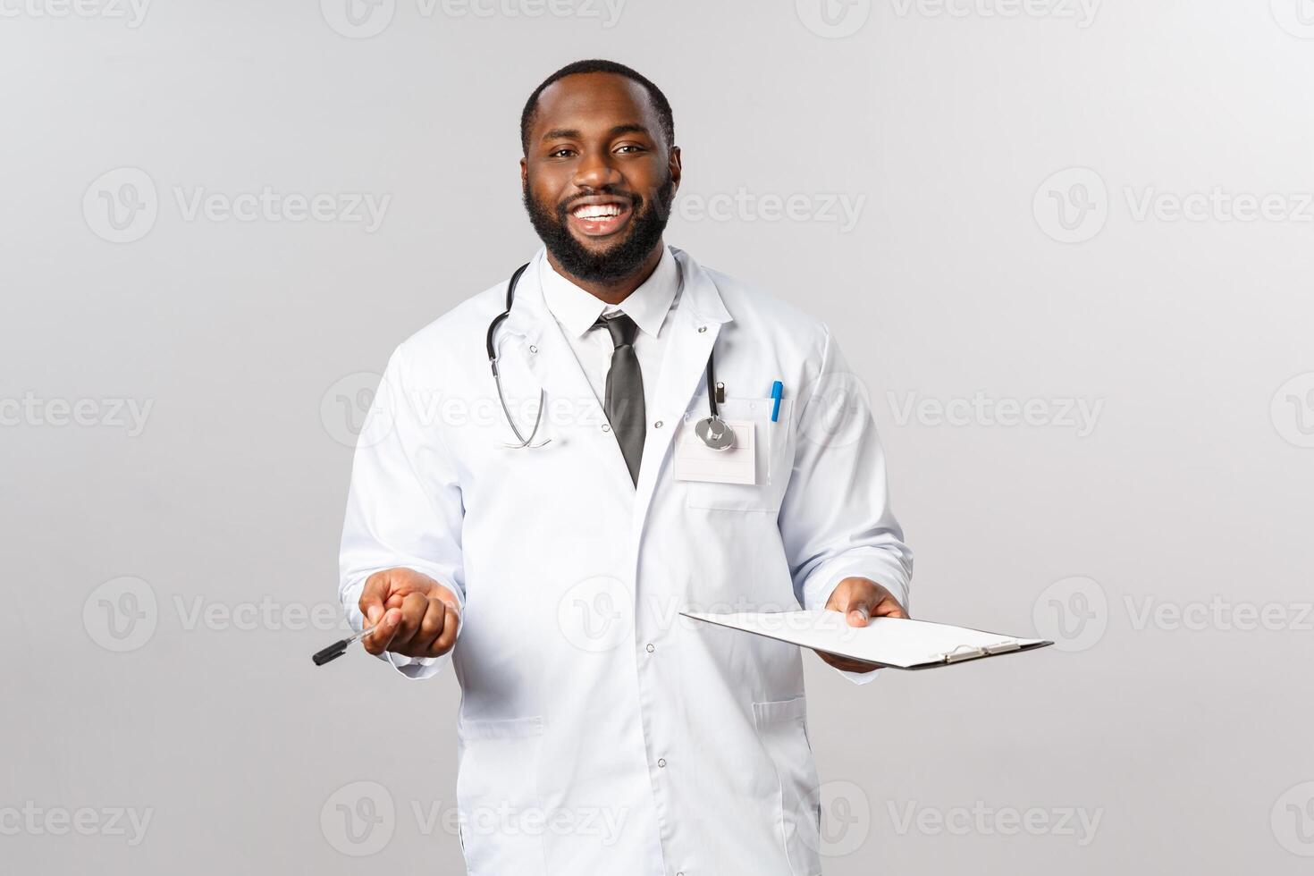 Medicine, covid19, treatment and hospital concept. Happy friendly african-american doctor, physician treating patient, have check-up in ambulance or hospital, smiling hold clipboard photo