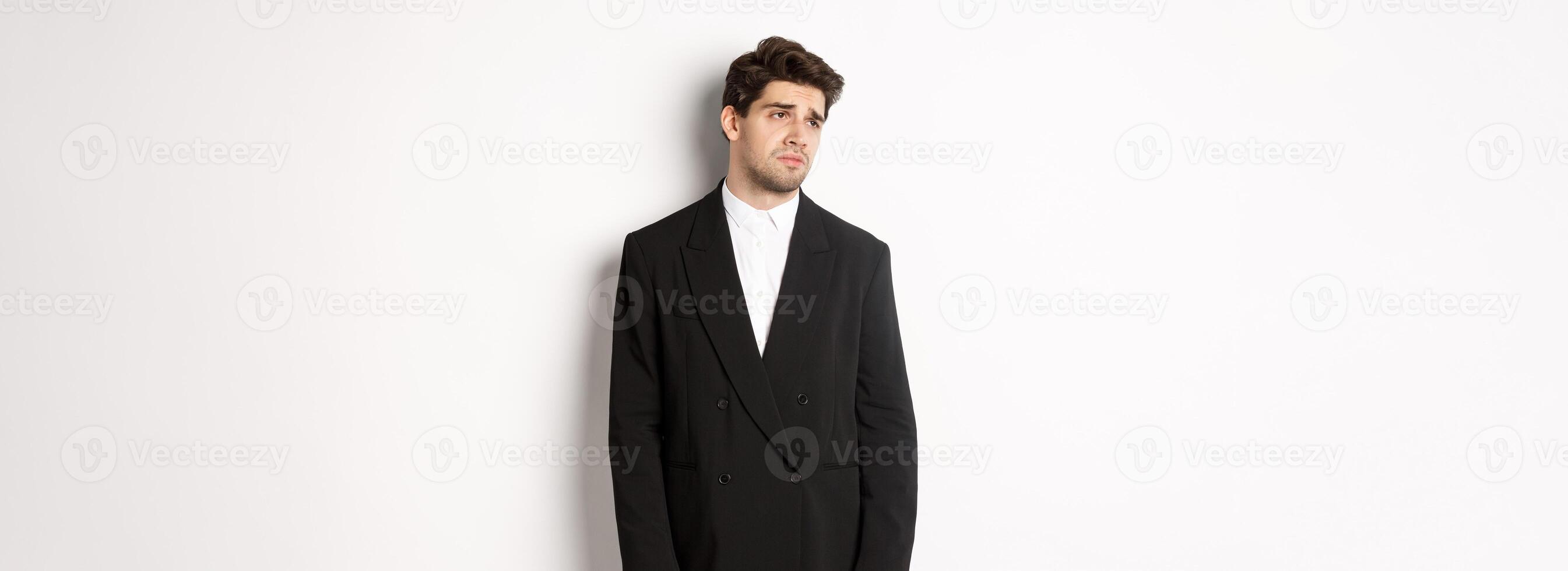 Image of tired man in suit looking left with distressed, gloomy expression, stare left at copy space, standing exhausted over white background photo