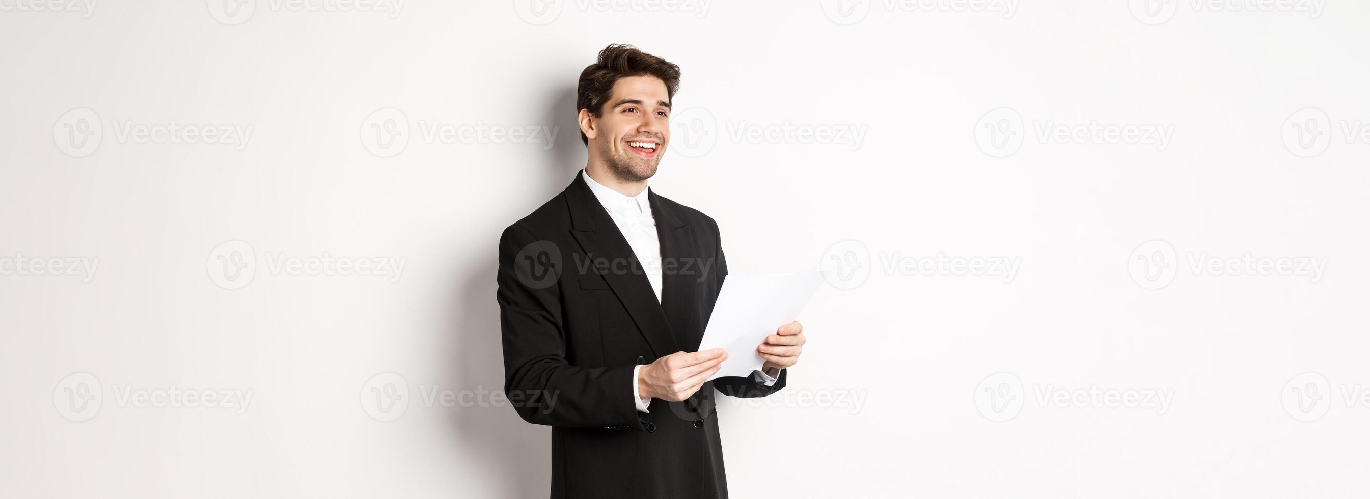 Image of handsome businessman in suit, holding documents and smiling, standing against white background photo