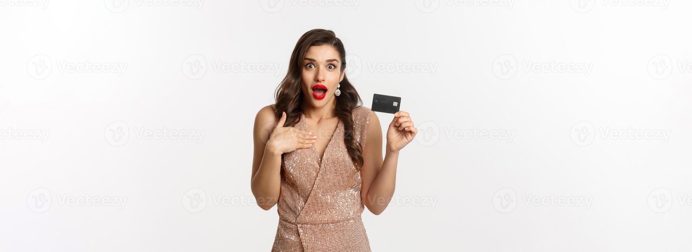 Holidays. christmas party and shopping concept. Amazed woman in stylish evening dress showing credit card, standing over white background photo