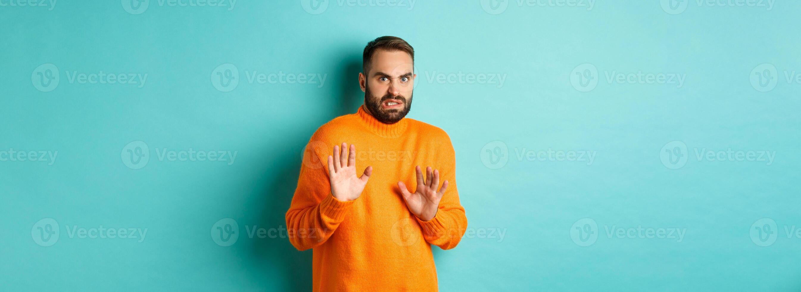 Alarmed guy shaking hands in rejection, declining and stepping away scared, standing over light blue background photo
