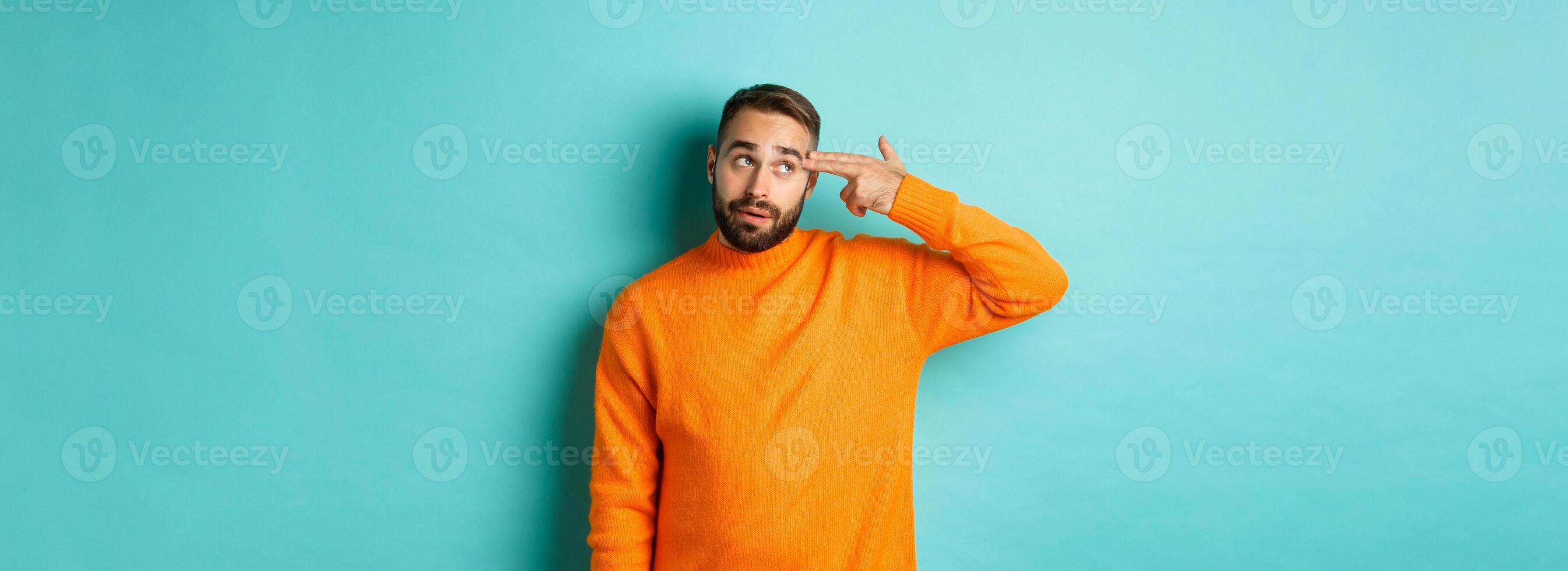 Man shooting himself in head, make finger gun near temple and roll eyes annoyed, standing bothered against light blue background photo