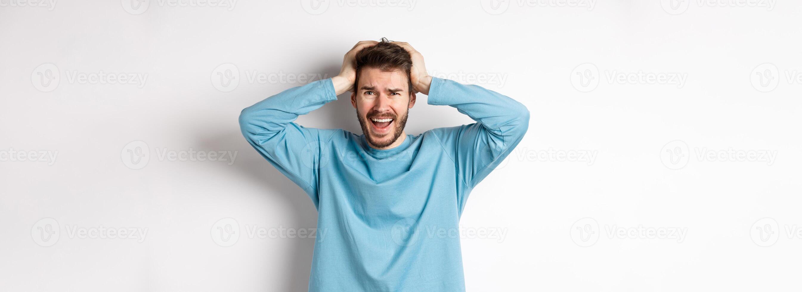Frustrated young man screaming in panic, standing anxious on white backgroud, panicking photo