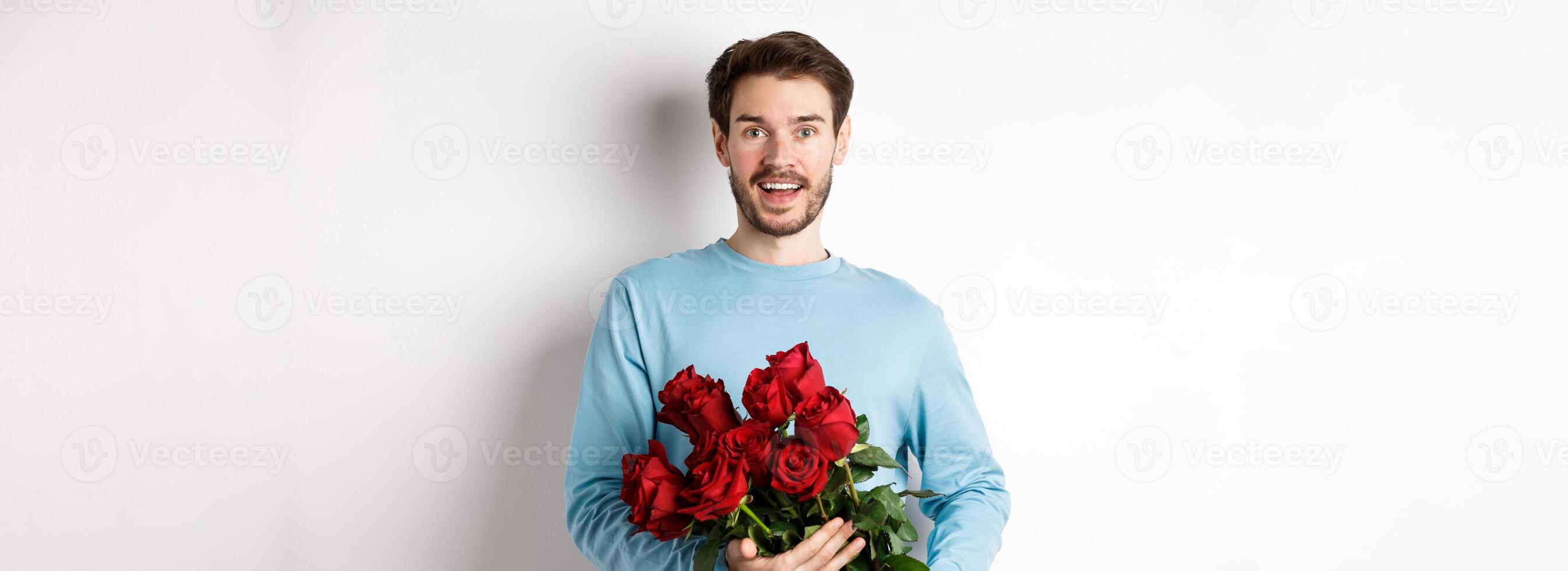 Romantic boyfriend bring beautiful bouquet of red roses on valentines day, having date with girlfriend, saying I love you, standing passionate on white background photo