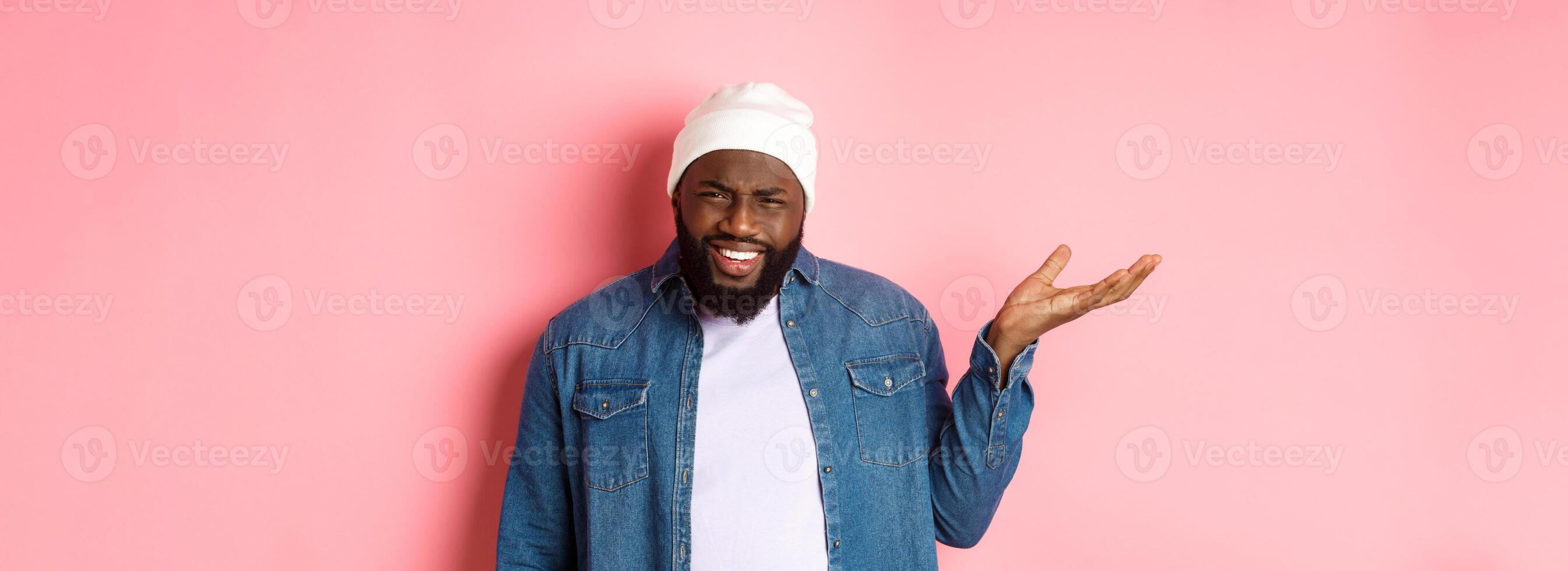 Annoyed and pissed-off african-american man pointing finger at head, scolding someone stupid, staring bothered at camera, pink background photo