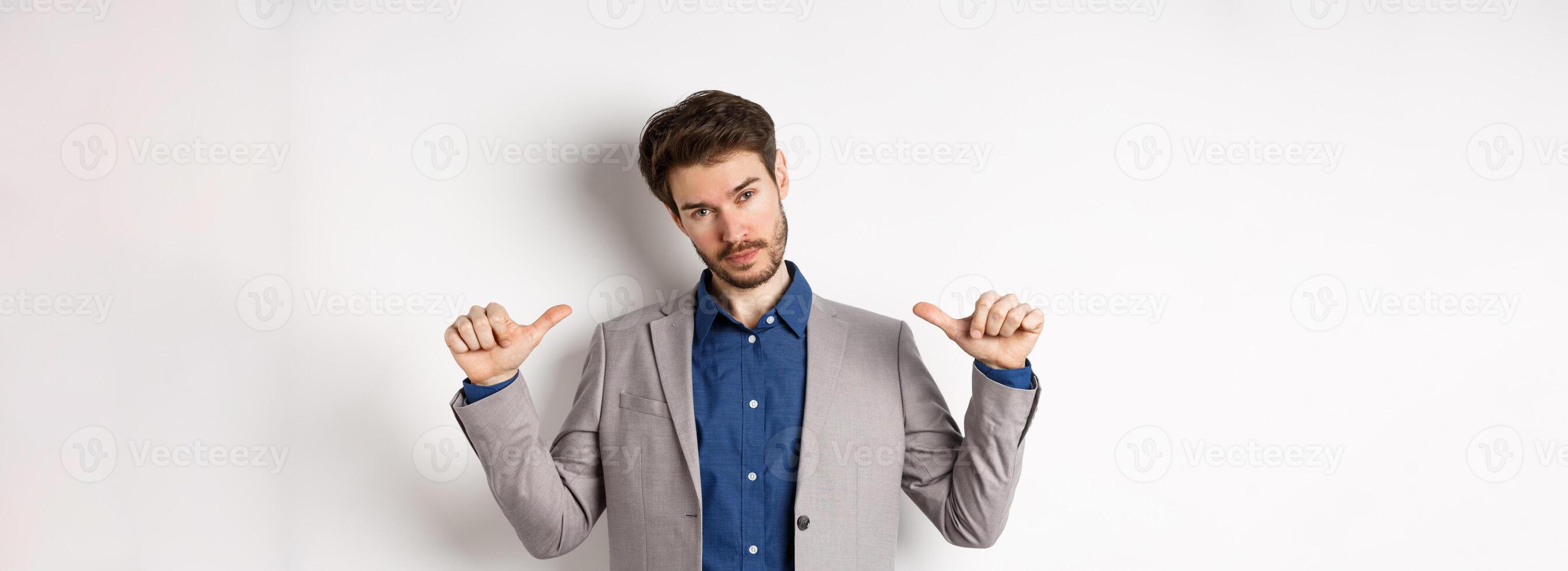 Confident man in business suit looking like professional, pointing at himself, self-promoting, standing on white background photo