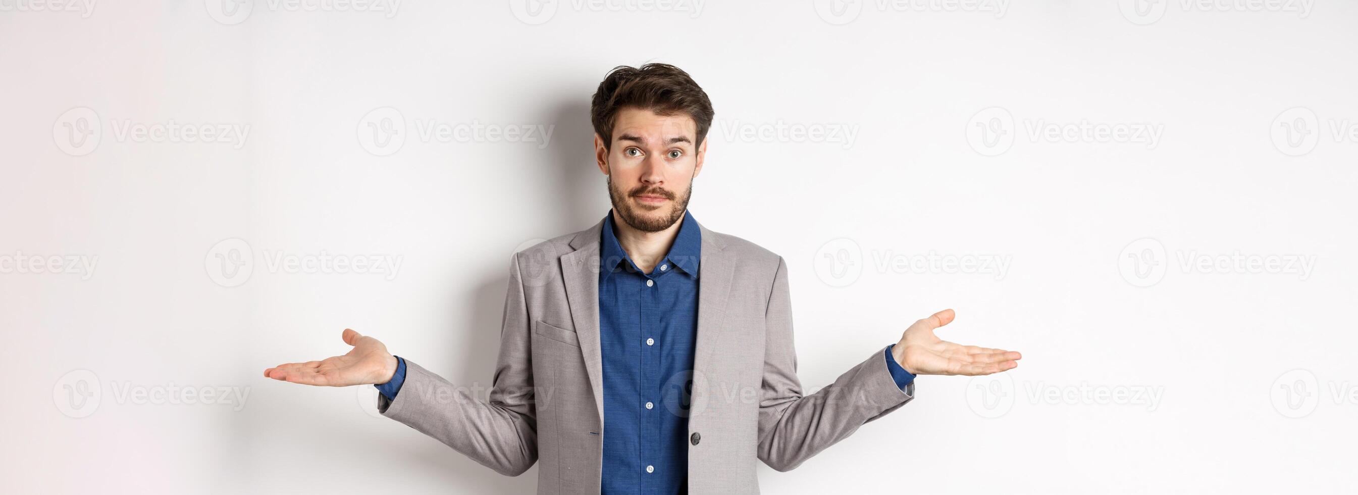 Dont know. Confused businessman spread hands sideways and look clueless, cant help, have no idea, standing on white background in suit photo