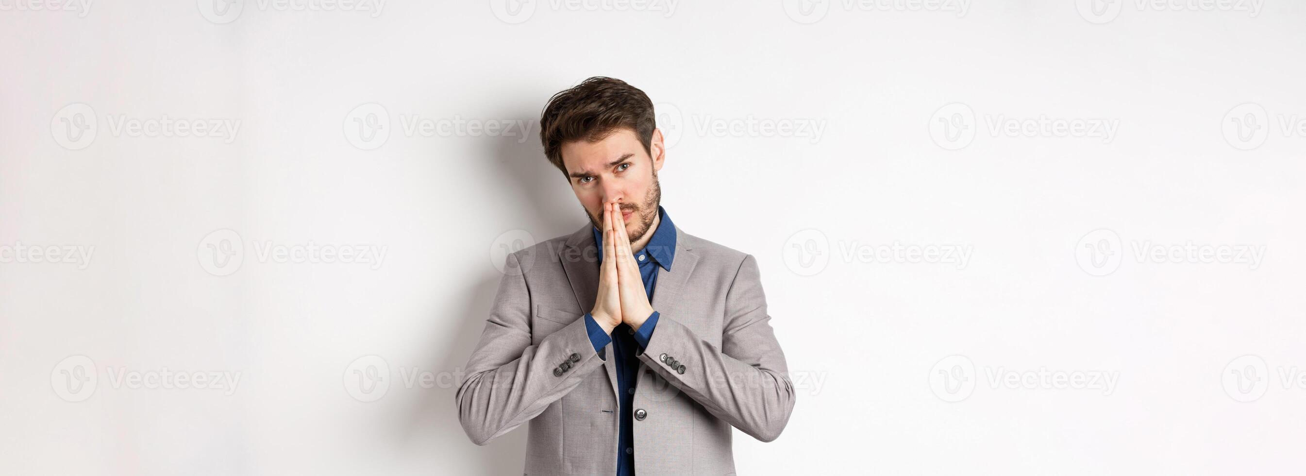 Please help. Pleading man in suit asking for favour, begging you, standing on white background photo