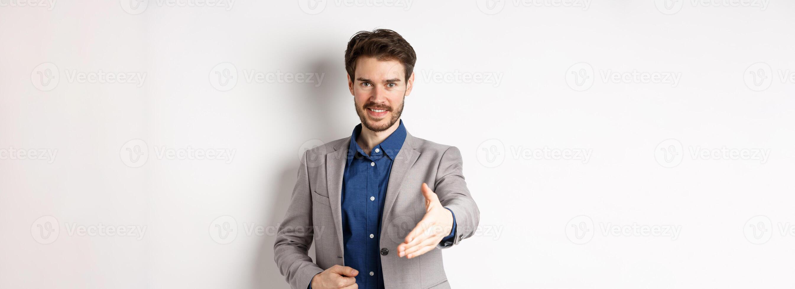 Confident businessman stretch out hand for business handshake and smiling, introduce himself on meeting, standing on white background photo