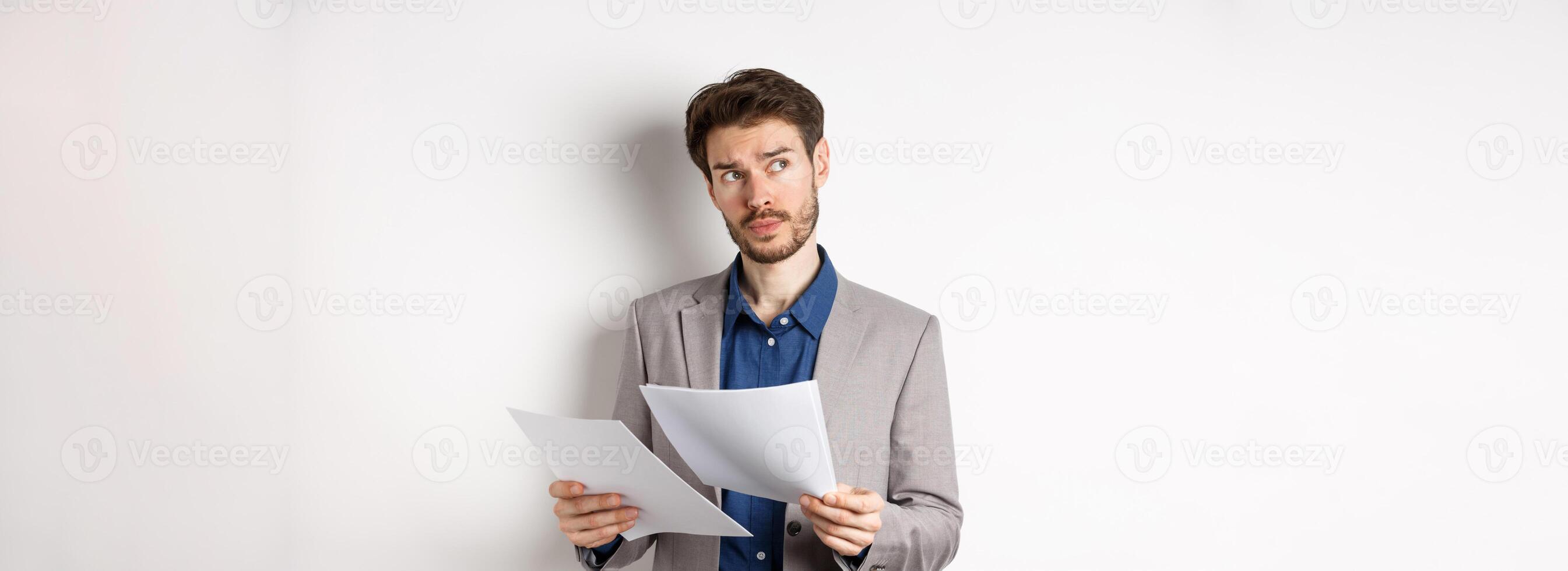 Businessman in suit looking through papers, reading documents at work and thinking, looking aside at logo, standing busy on white background photo