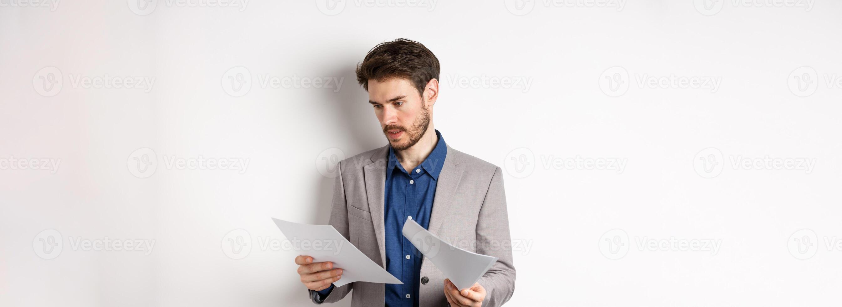 Businessman in suit looking through papers, reading documents at work, standing busy on white background photo
