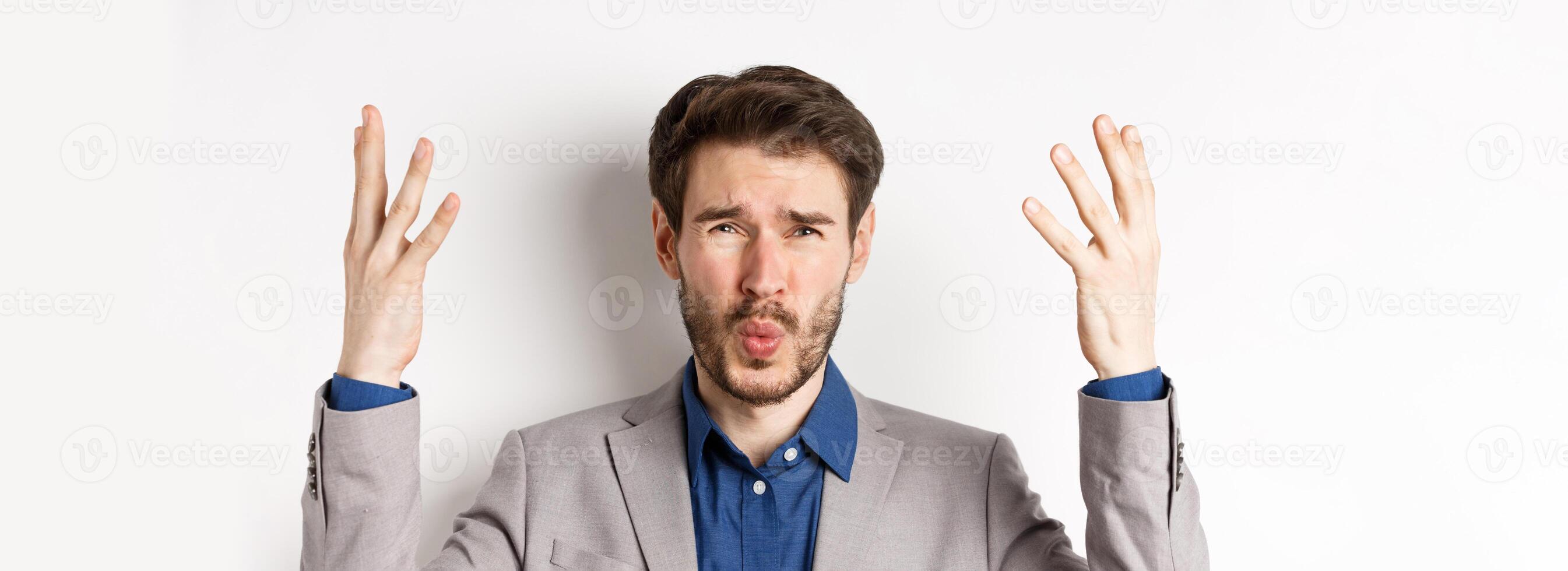 Frustrated businessman shaking hands and asking wtf what happened, looking disappointed and shocked at camera, scolding employee, white background photo
