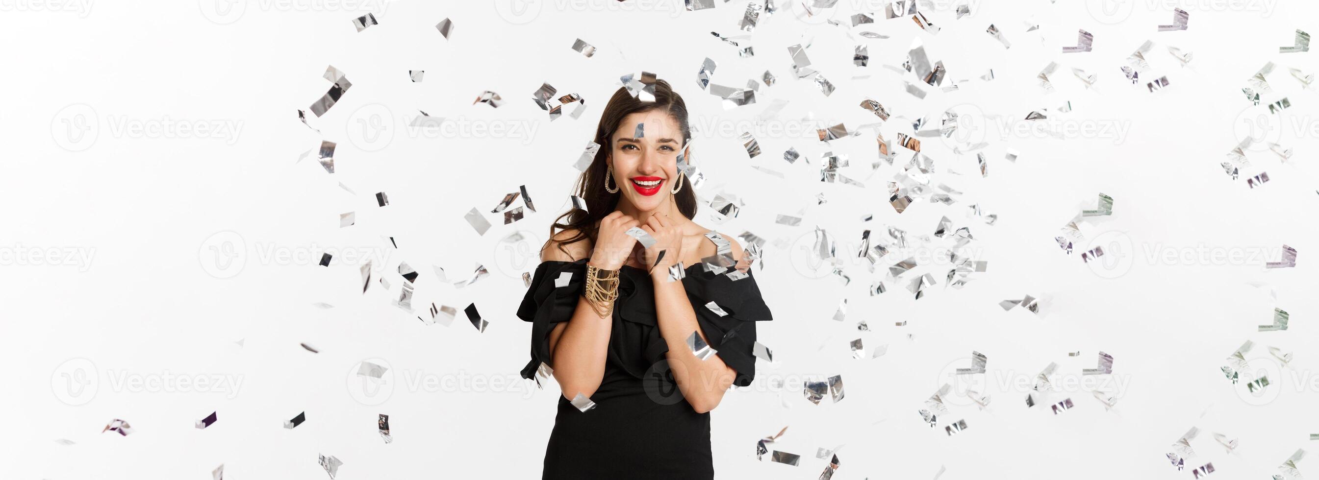 Happy woman celebrating winter holidays, smiling cheerful, partying on New Year with confetti, standing over white background photo