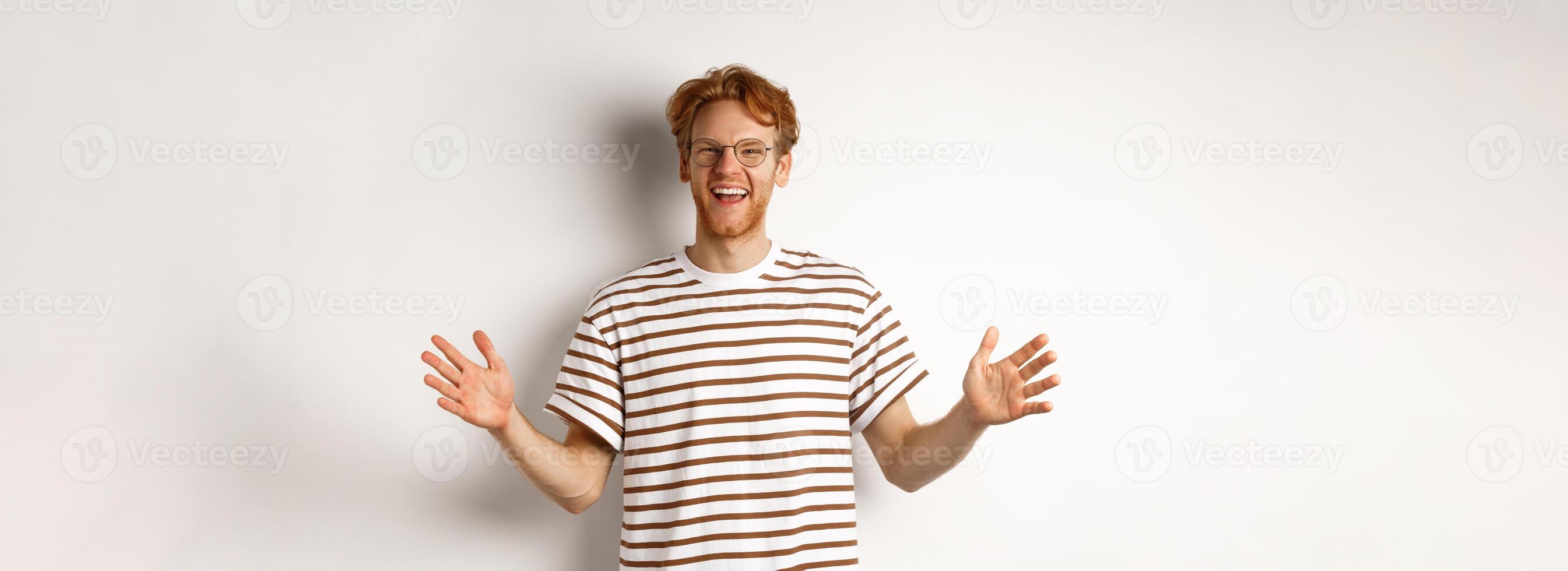 Attractive young man with red hair and glasses showing large size, length of big object, smiling satisfied, standing over white background photo