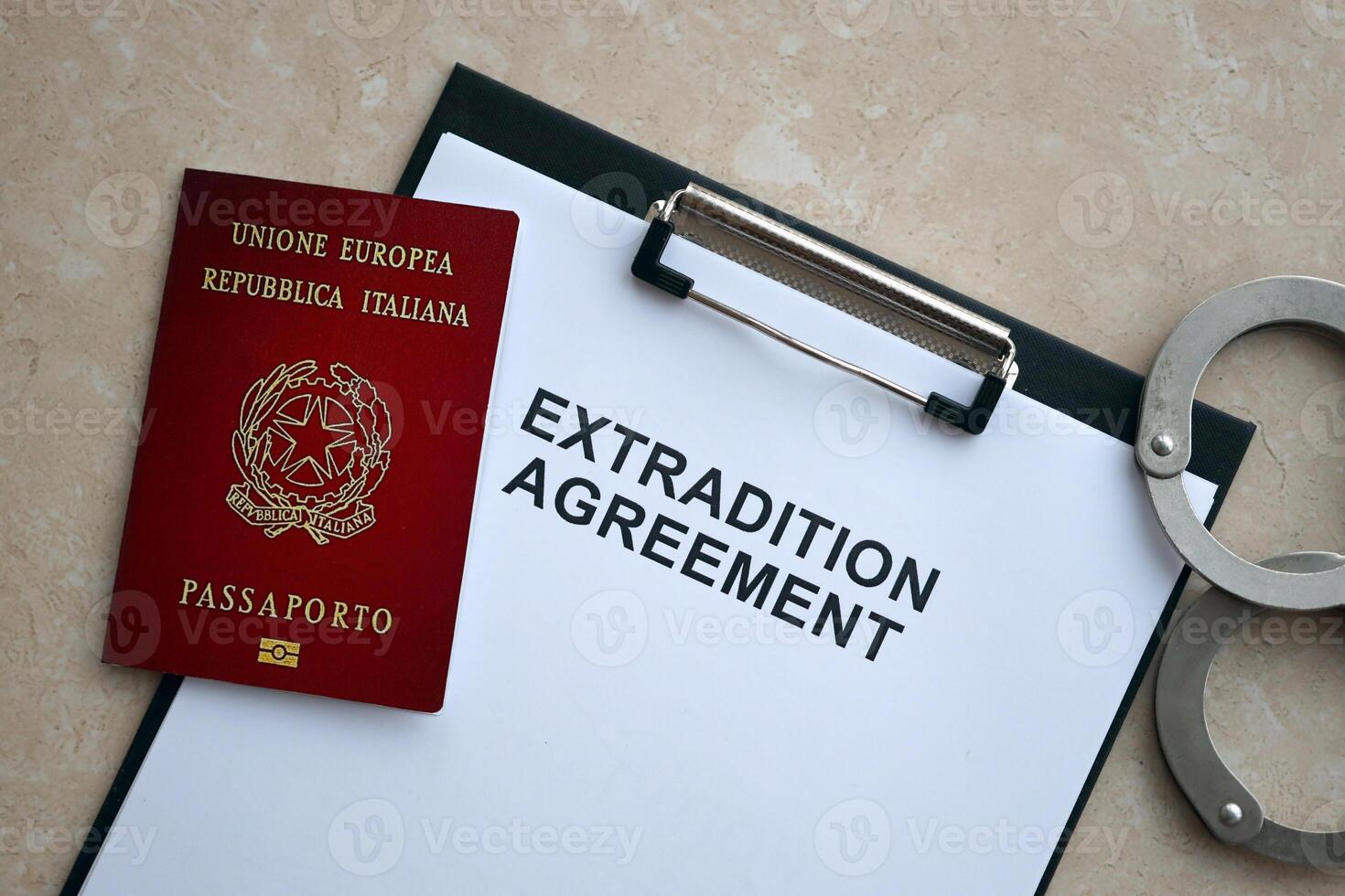 Passport of Italy and Extradition Agreement with handcuffs on table photo