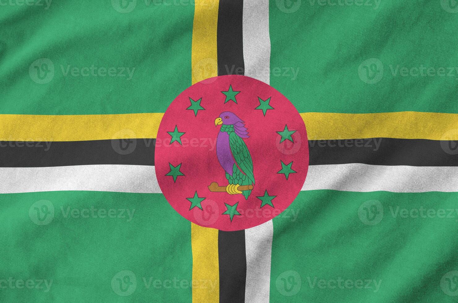 Dominica flag depicted on folded wavy fabric of old cloth photo