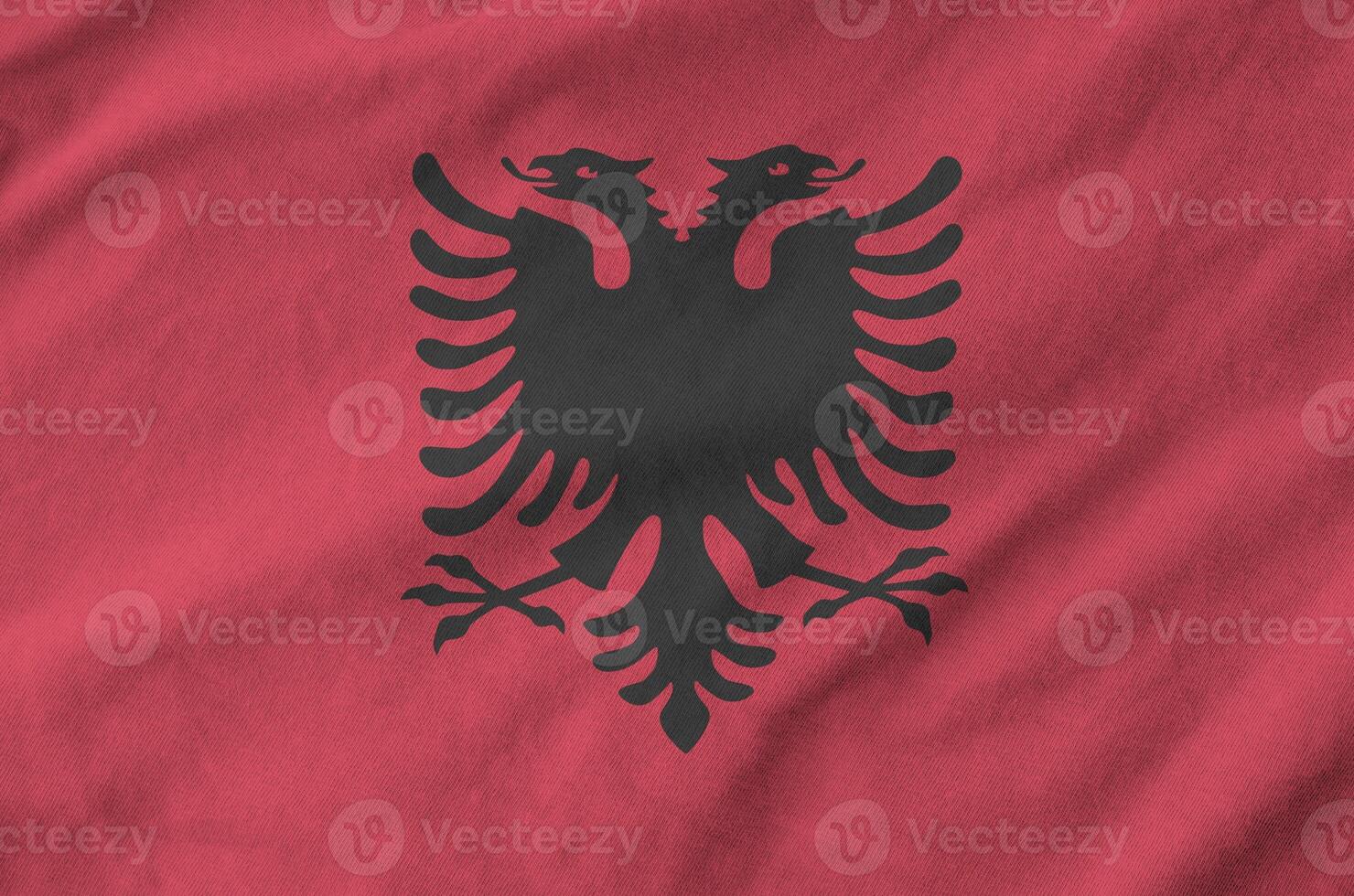 Albania flag depicted on folded wavy fabric of old cloth photo