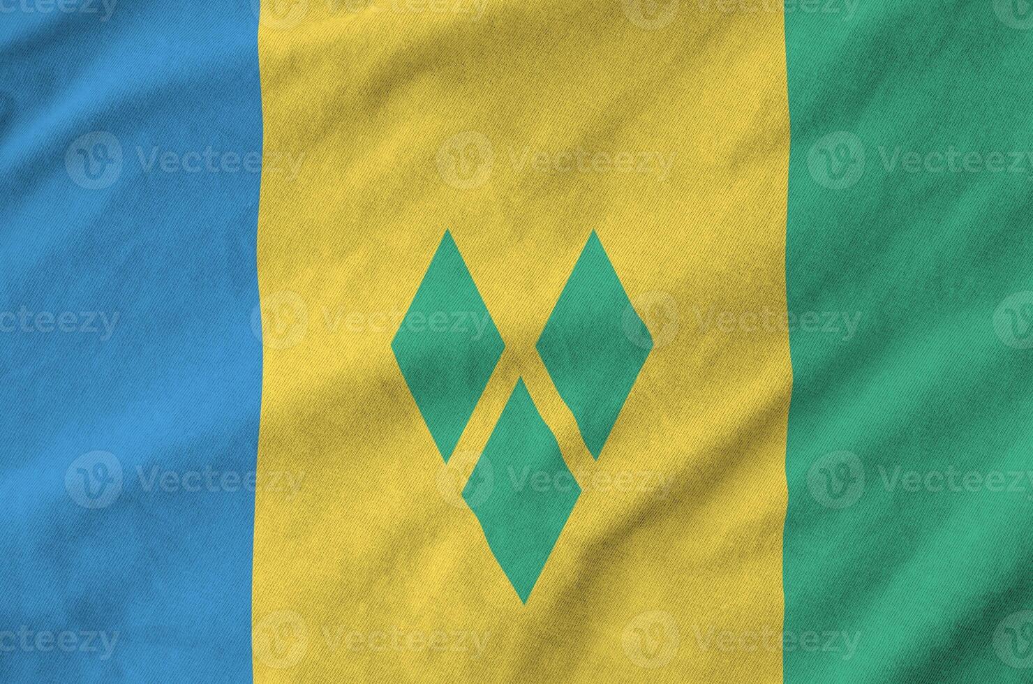 Saint Vincent and the Grenadines flag depicted on folded wavy fabric of old cloth photo