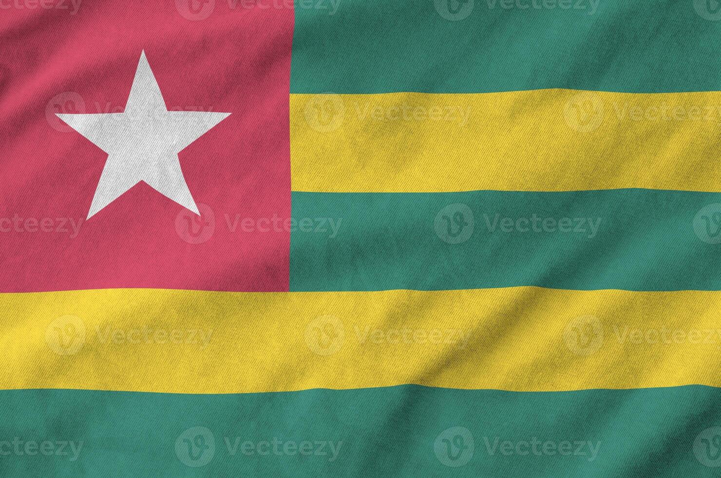 Togo flag depicted on folded wavy fabric of old cloth photo
