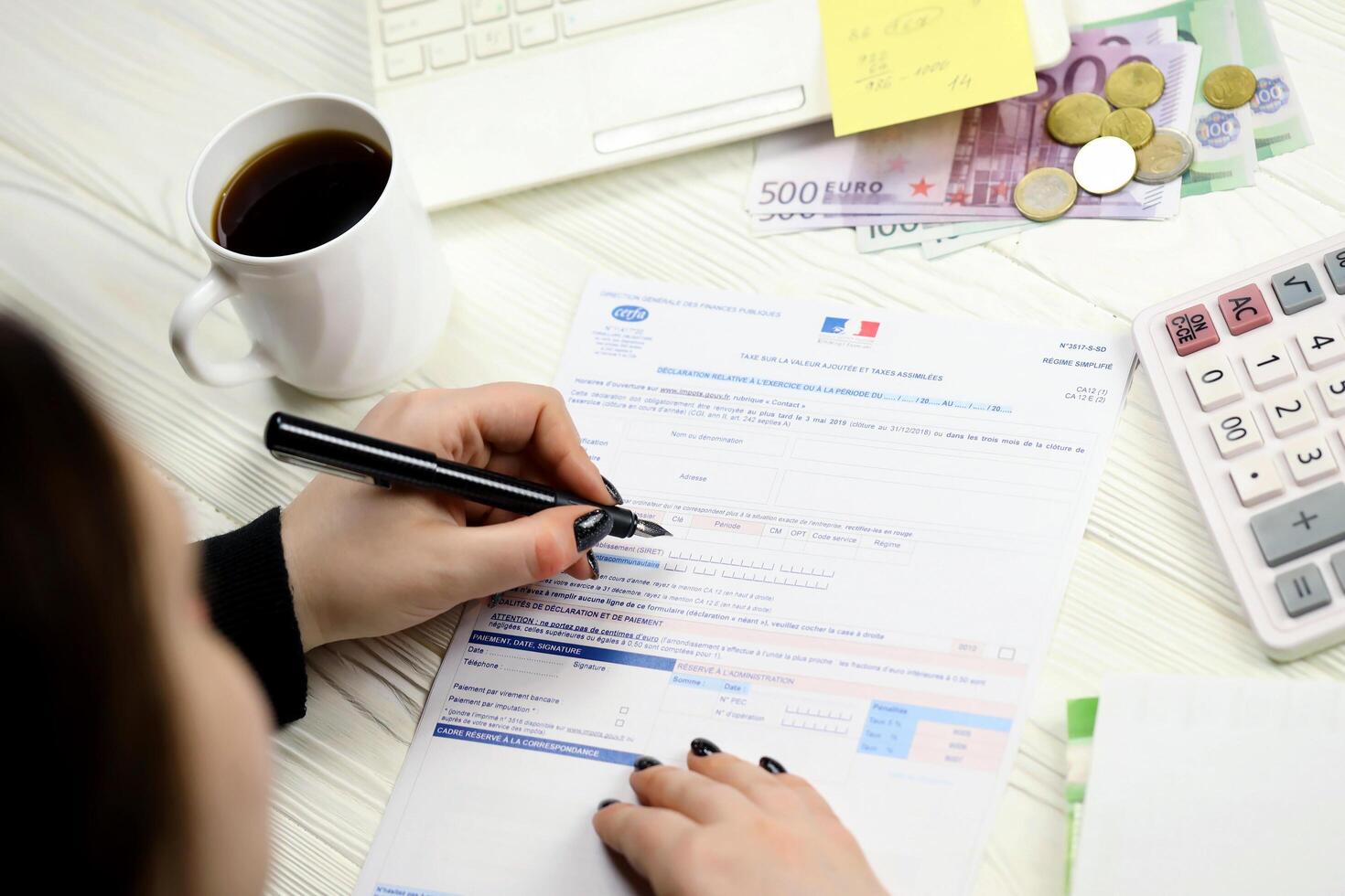 KYIV, UKRAINE - OCTOBER 31, 2023 Accountant fill french tax form CA12 Value added tax and similar taxes in end of tax period. Taxation and paperwork routine photo