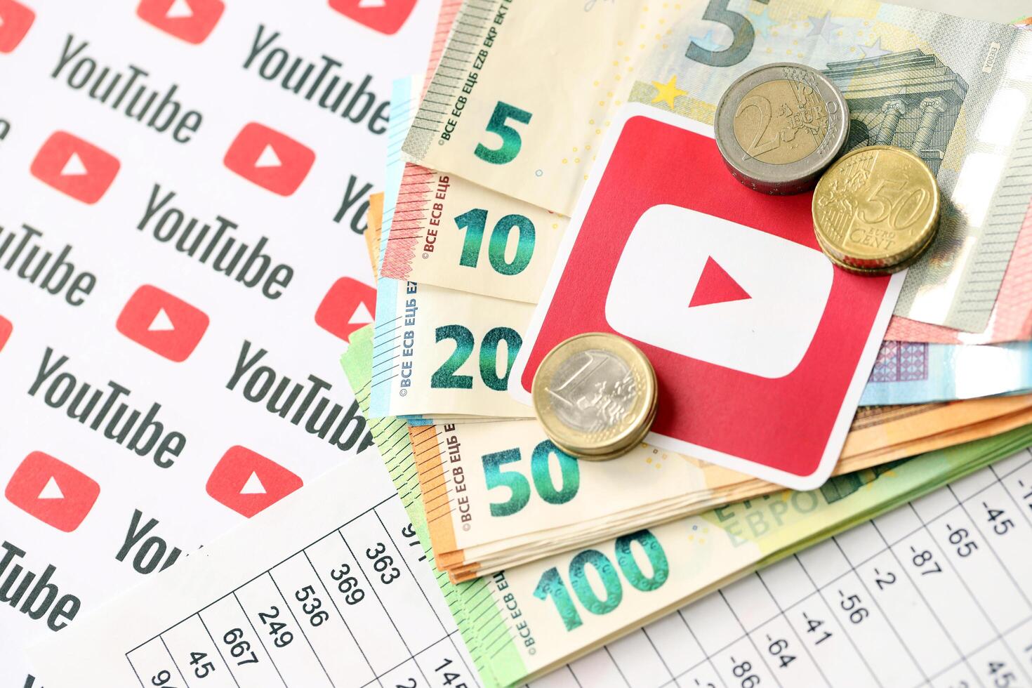 KYIV, UKRAINE - APRIL 20, 2024 YouTube logo and many euro money bills. Symbol of famous social network platform and european currency banknotes photo